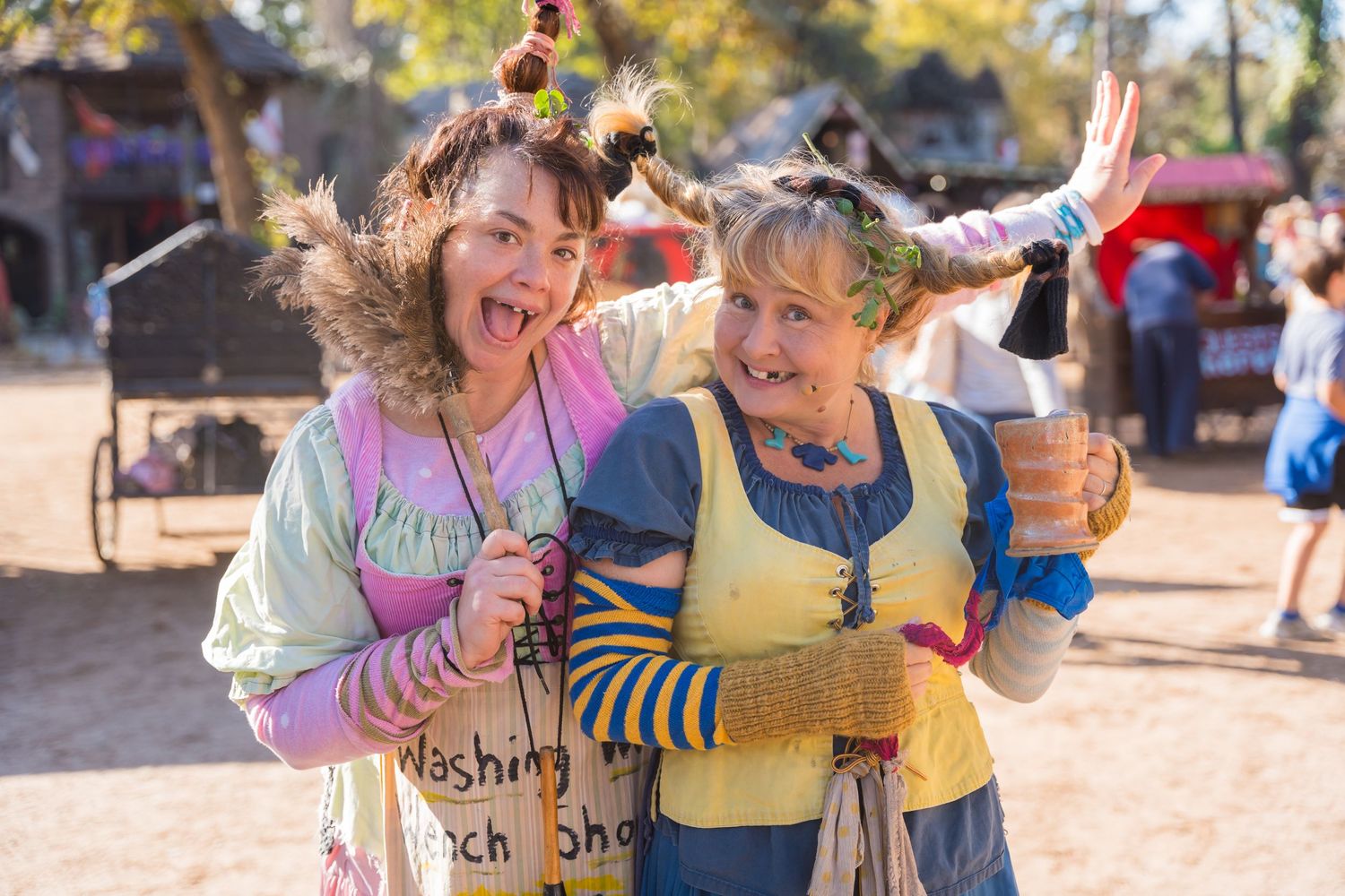 Two costumed performers make silly expressions while posing at a renaissance festival.