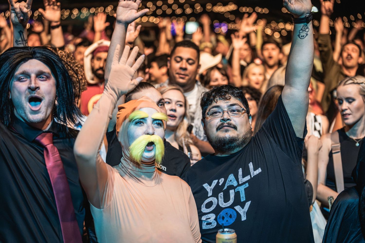 Energetic crowd with painted faces and costumes cheering at a rock concert.