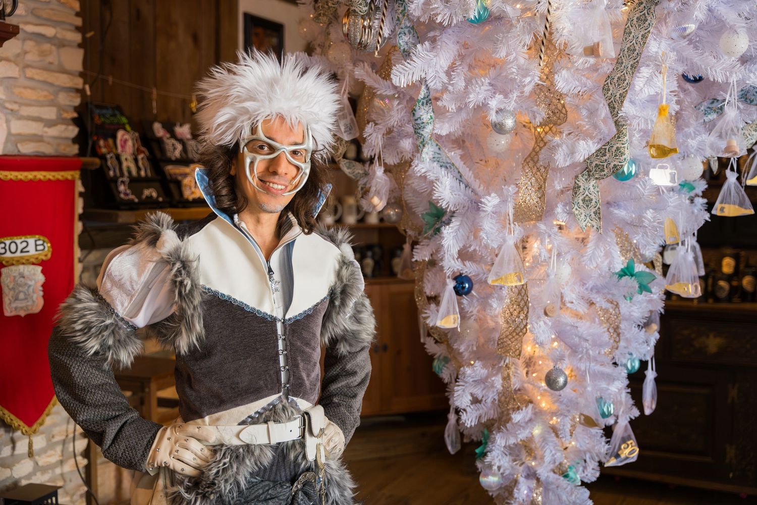 Festival participant in winter attire posing in front of a decorated white holiday display.
