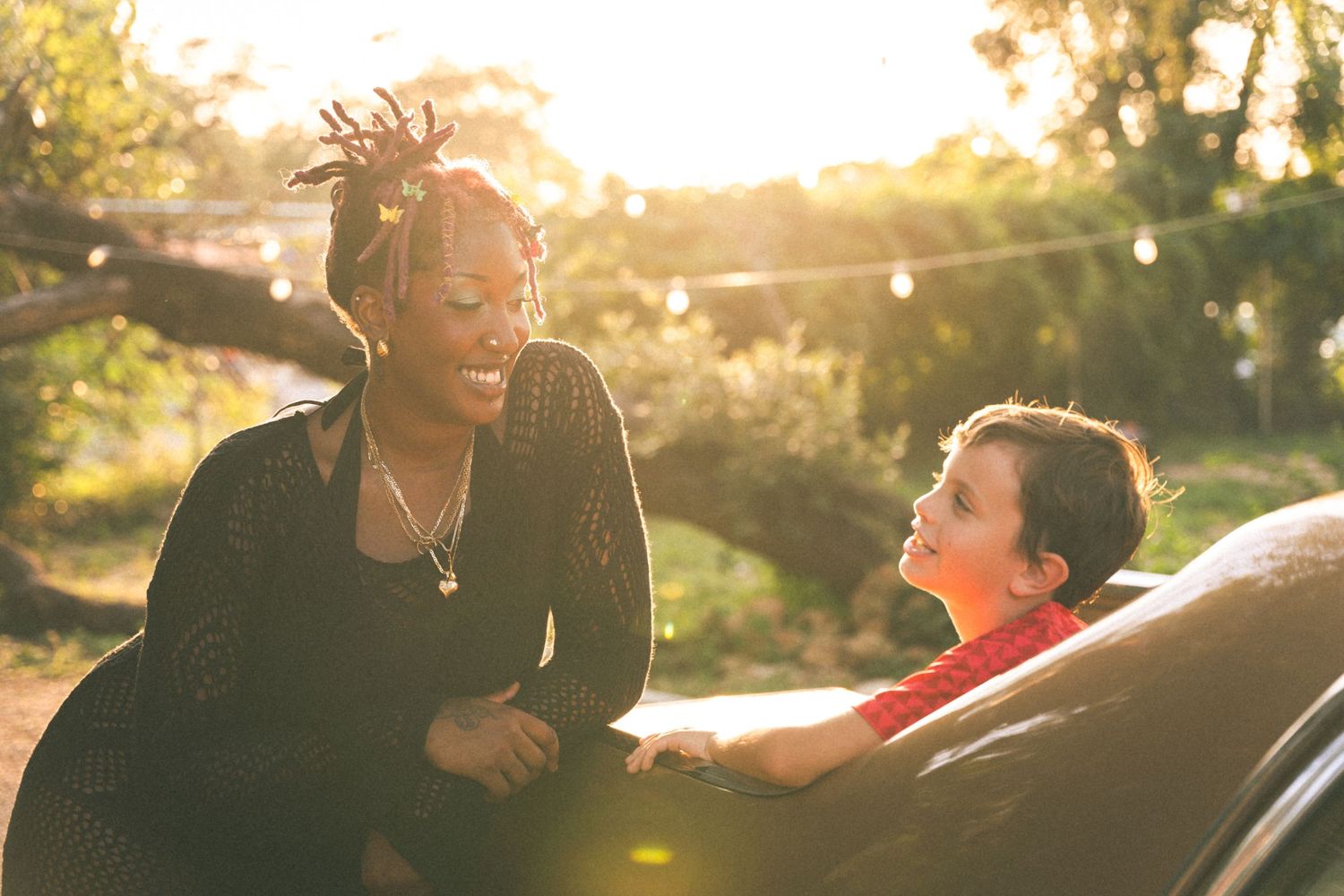 Two people share a candid laugh during sunset with golden light streaming through the background.