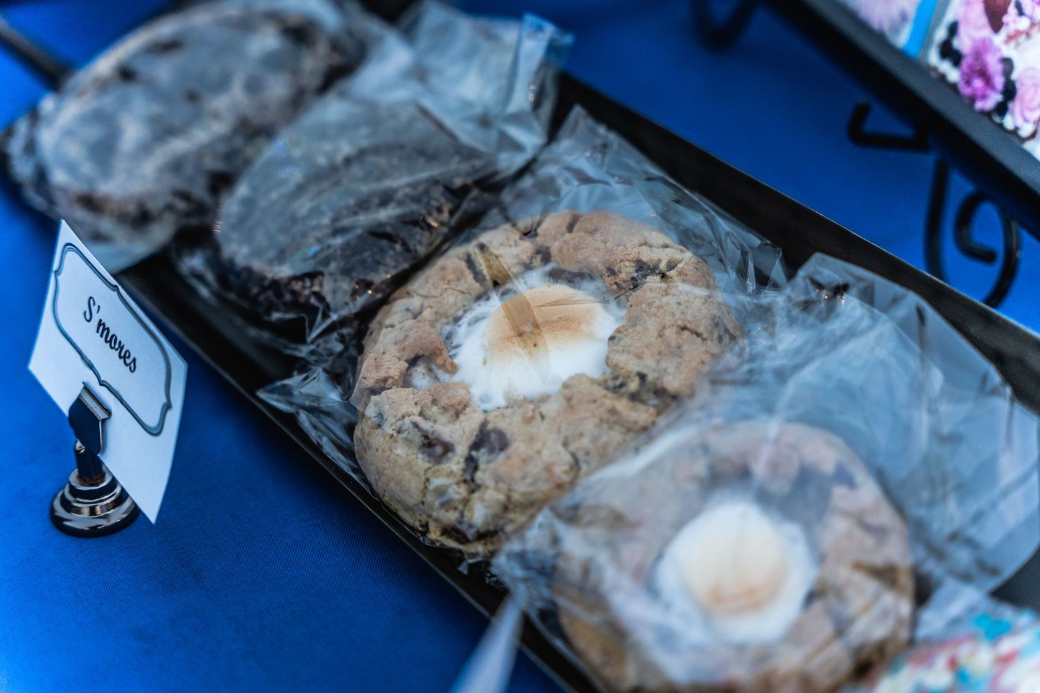 Various cookies and baked goods displayed with labels on blue tablecloth.