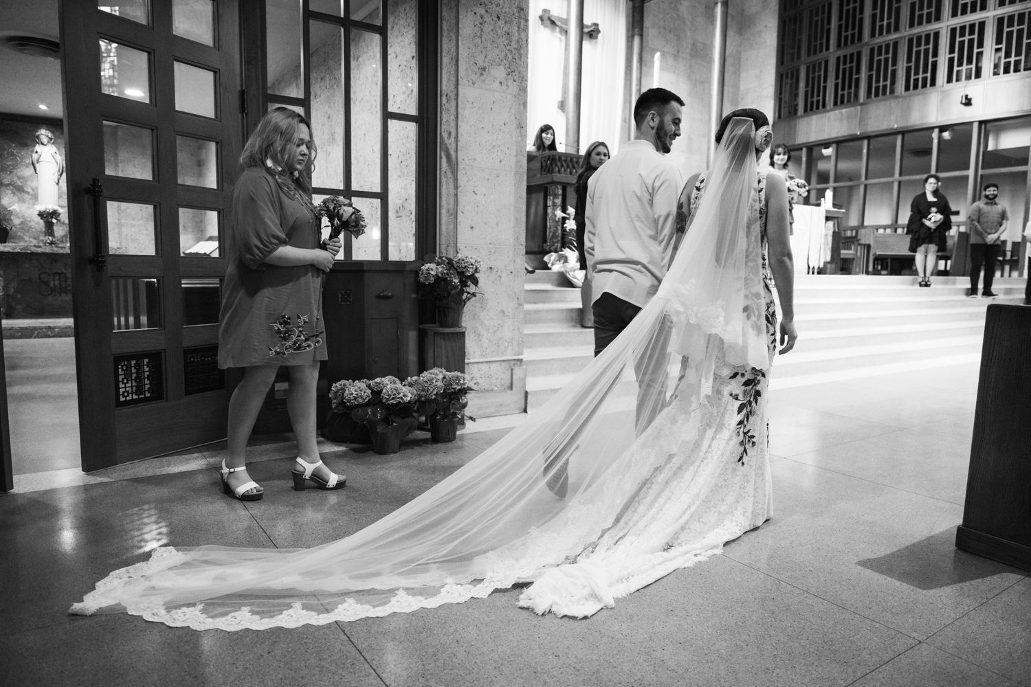 Elegant wedding couple walking with flowing long veil in black and white.