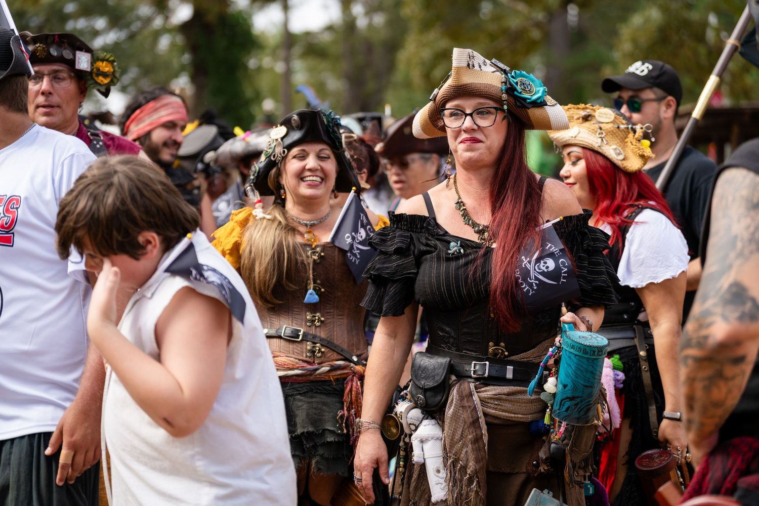 Festival goers dance and celebrate together at an outdoor music event during daytime.