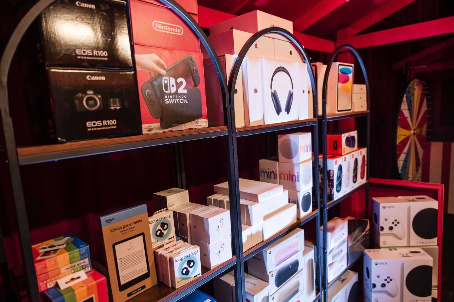 Multiple Canon cameras and photography accessories arranged on wooden retail display shelves.