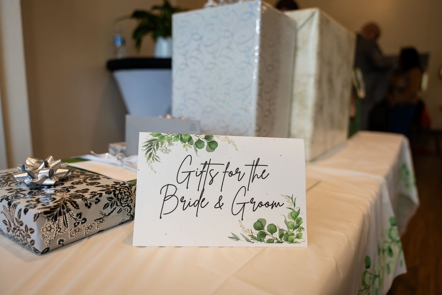 White wedding place cards with greenery designs sit elegantly on a table at a reception venue.