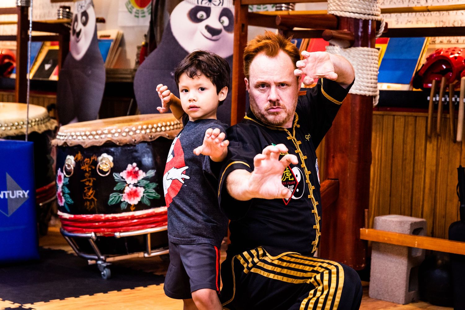 Diverse group of people practicing martial arts moves in a training studio with wooden floors and walls.
