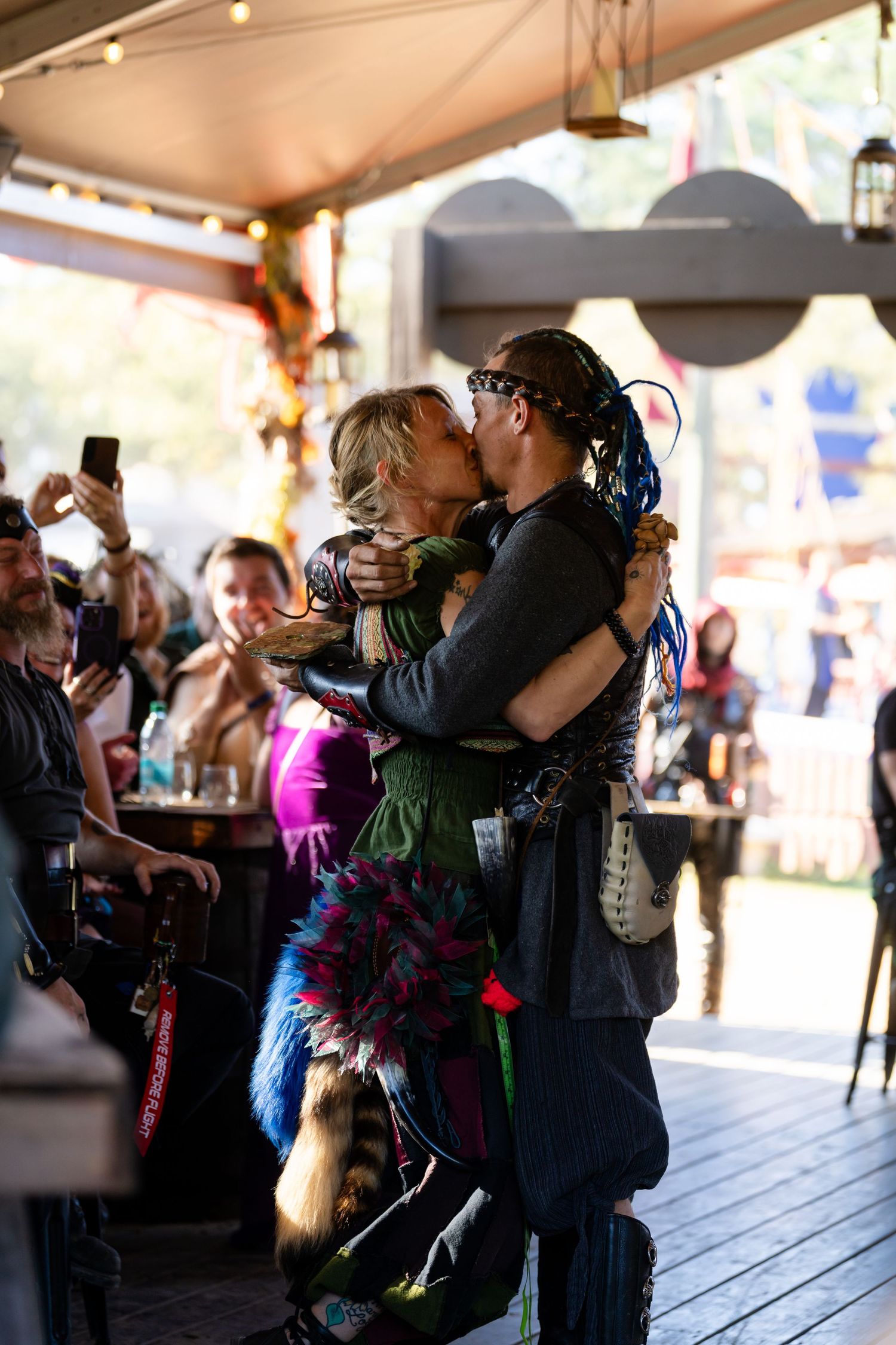 People dance together at an indoor event venue with string lights overhead and colorful decorative elements.