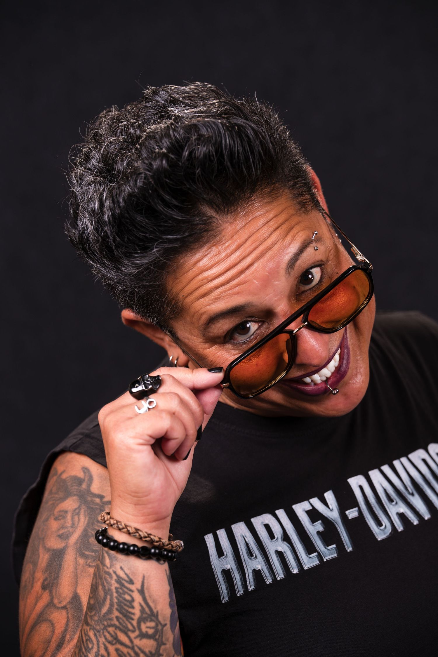 A series of dark artistic portraits showing someone wearing sunglasses and a Harley-Davidson shirt against a black background.