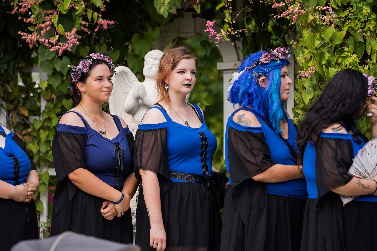 A group of people wearing coordinated blue and black formal attire stand together at an outdoor event.