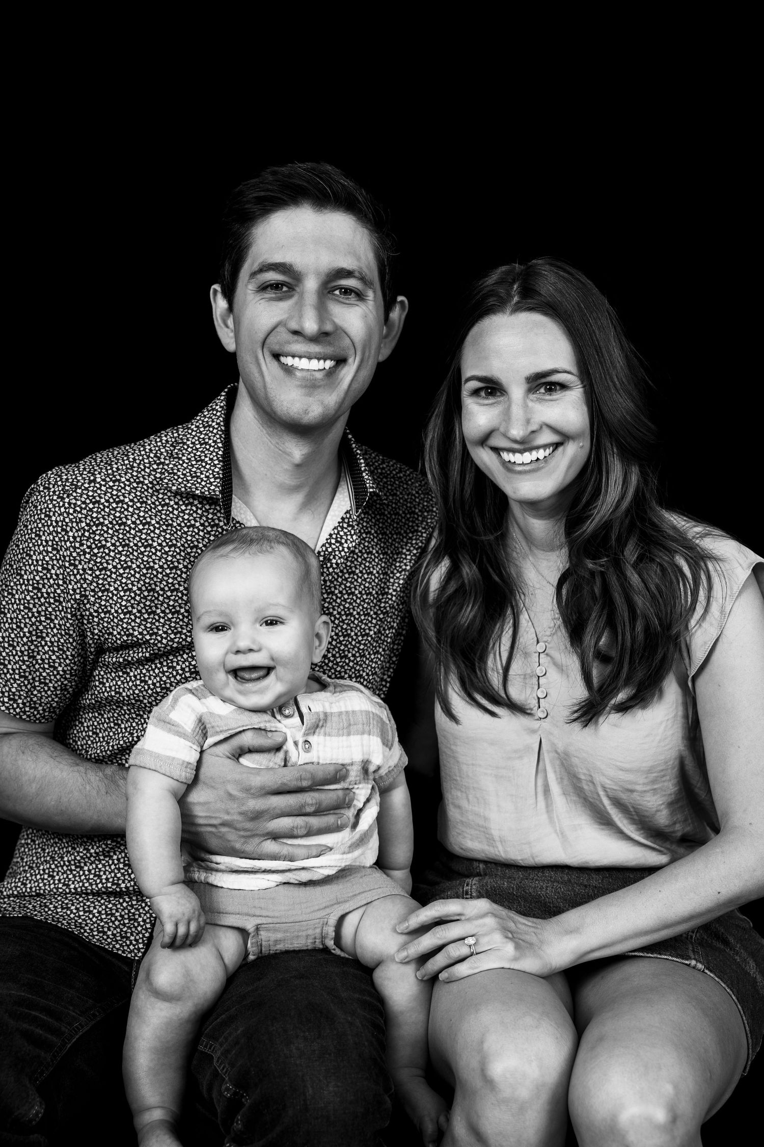 A series of black and white family photos showing a baby and parents sitting together on a couch in progressive shots.