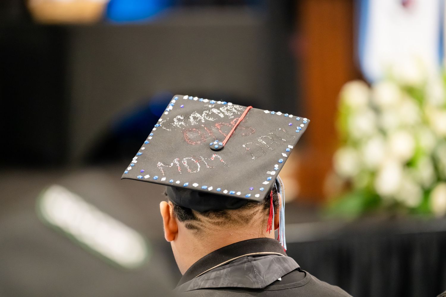 Graduate wearing decorated black mortarboard cap at college commencement ceremony.