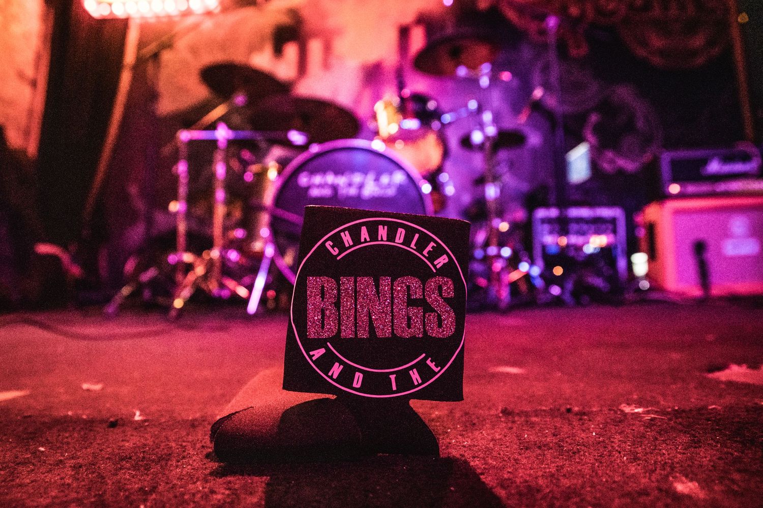 Branded merchandise patch or sticker with text reading 'Bings' under moody red stage lighting.