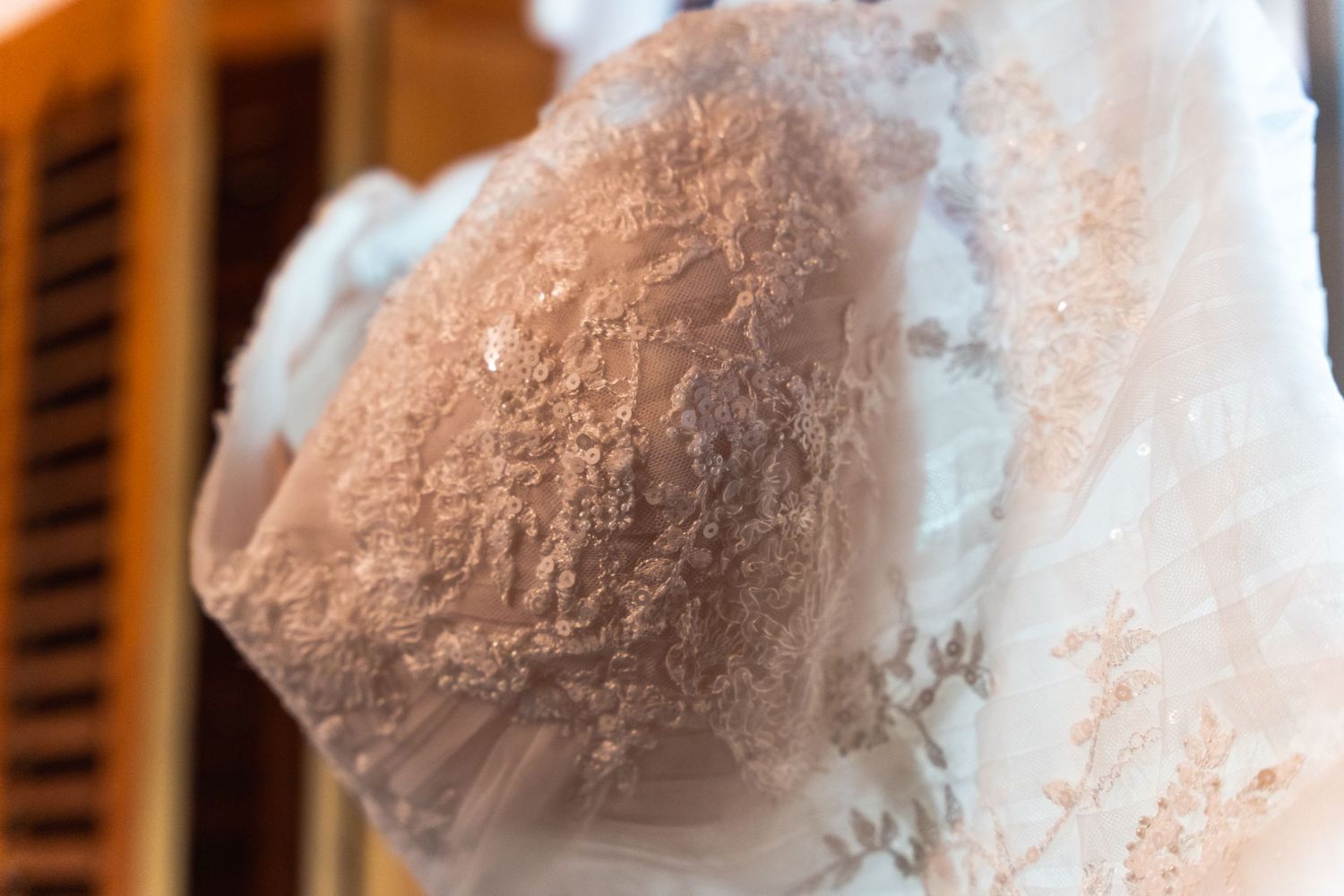 Close-up detail of delicate lace pattern on white wedding dress fabric.