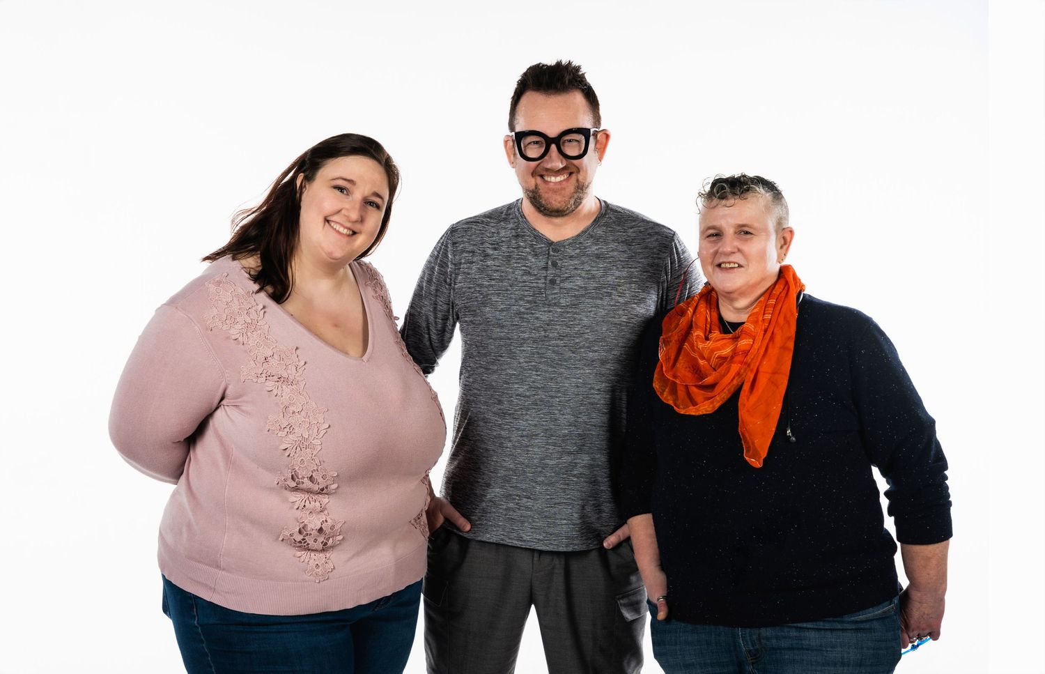 Three people posing together against a white background in casual attire.