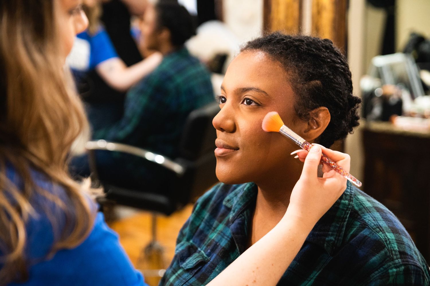 Someone getting makeup applied with a brush in a salon setting.