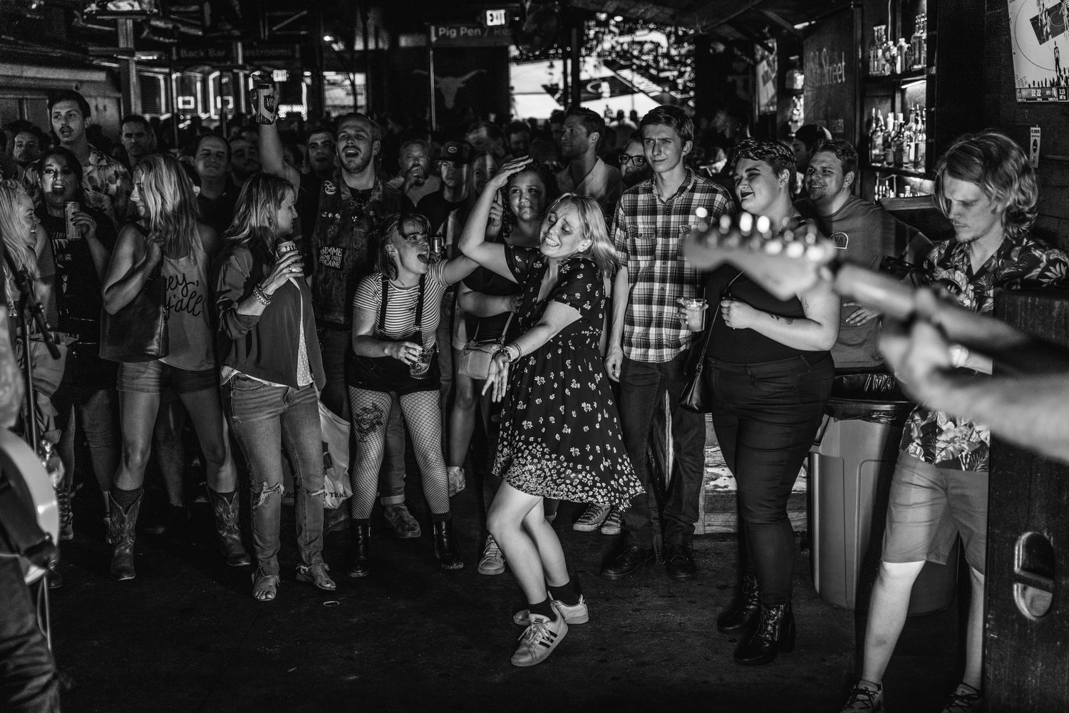 Black and white photo of crowd dancing and enjoying live music in a bar setting.