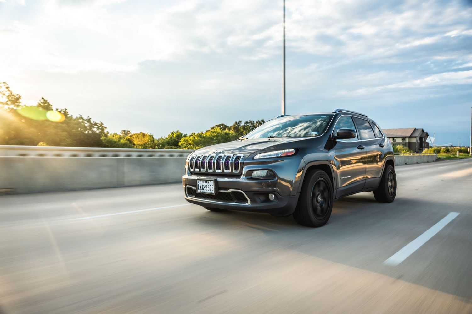 Modified Jeep Cherokee with blacked-out trim photographed in motion.