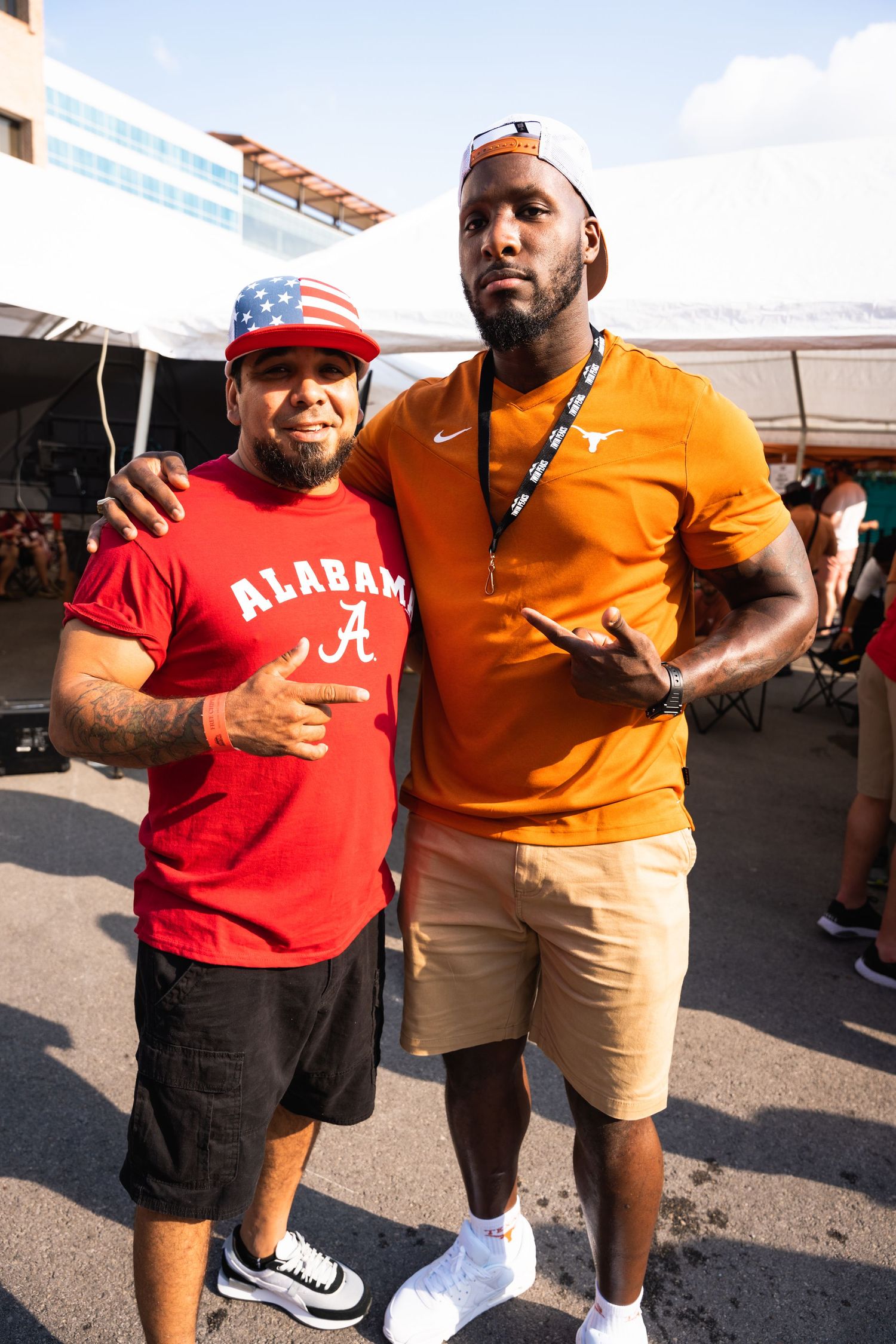 Two sports fans in team gear pose together at outdoor event.