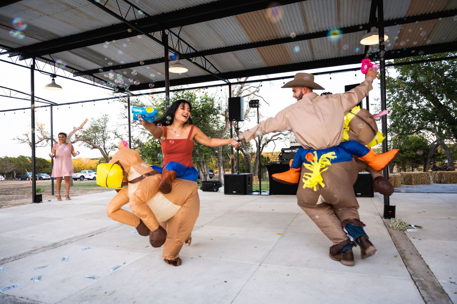 Two dancers in orange and blue inflatable sumo costumes performing energetic moves on an outdoor stage.