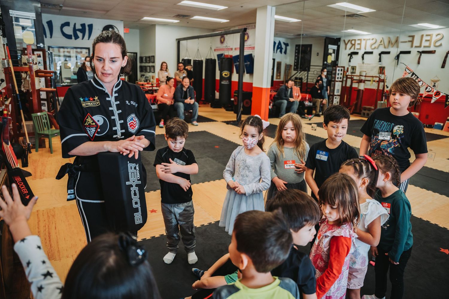 Instructor leads a martial arts class demonstration for a group of children in a training facility.