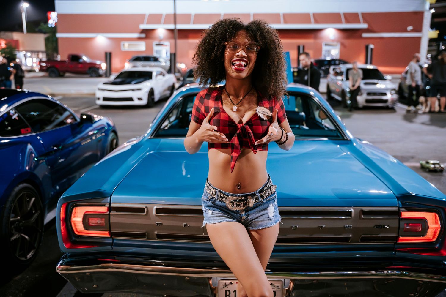 Energetic outdoor photoshoot with model on classic car at night.