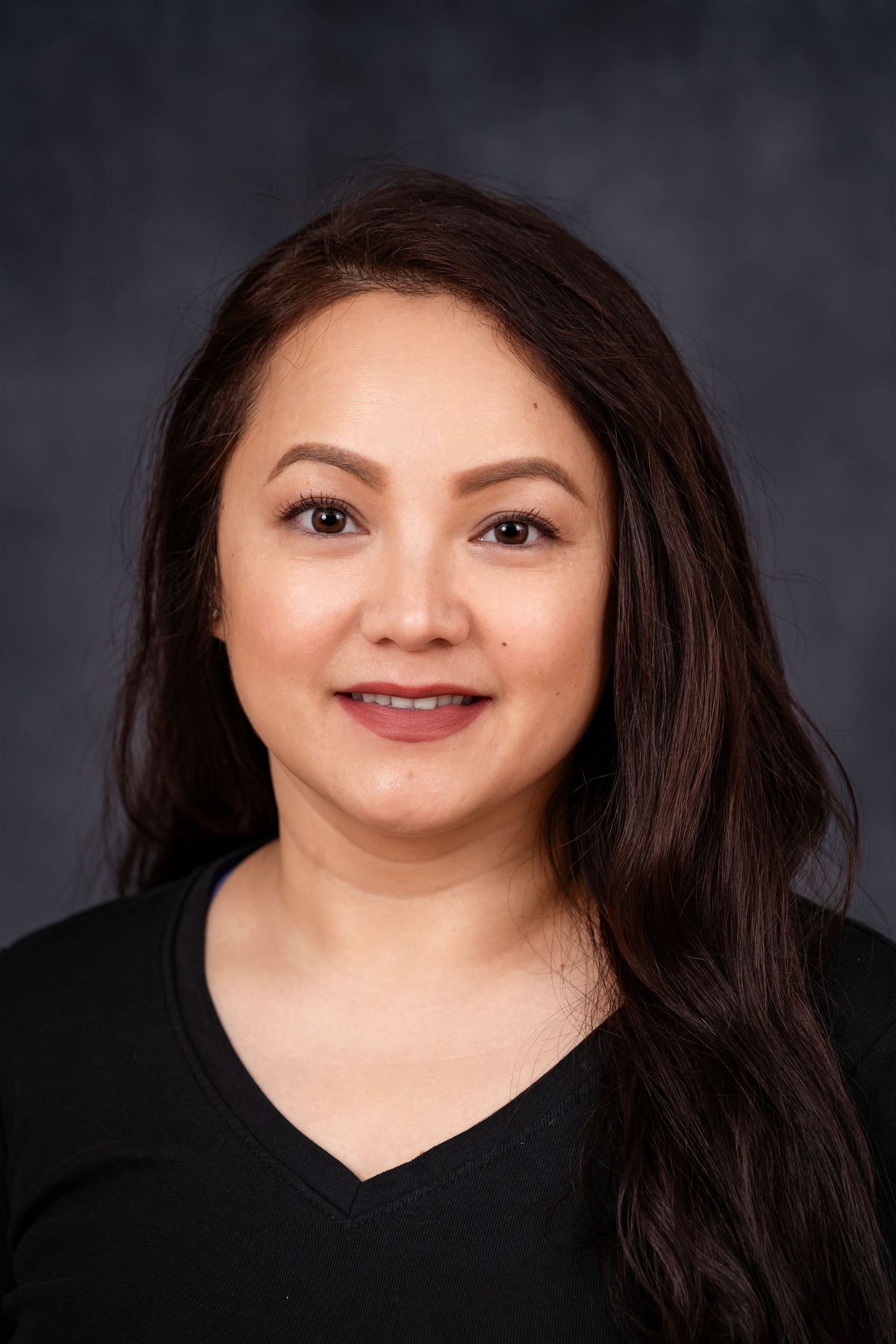 Professional headshot of a woman in black attire against dark studio background.