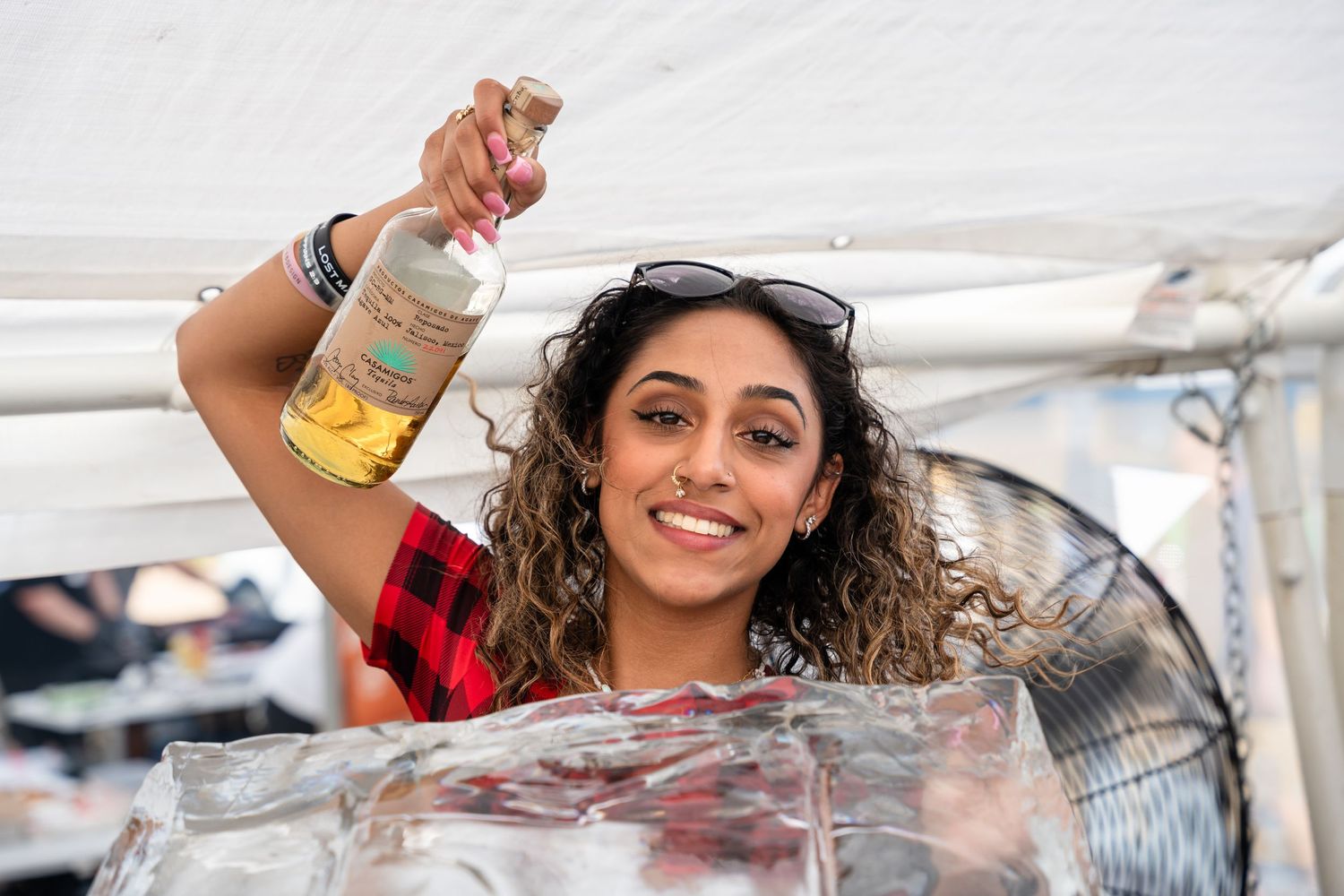 Staff member holding beverage bottle at outdoor promotional event tent.