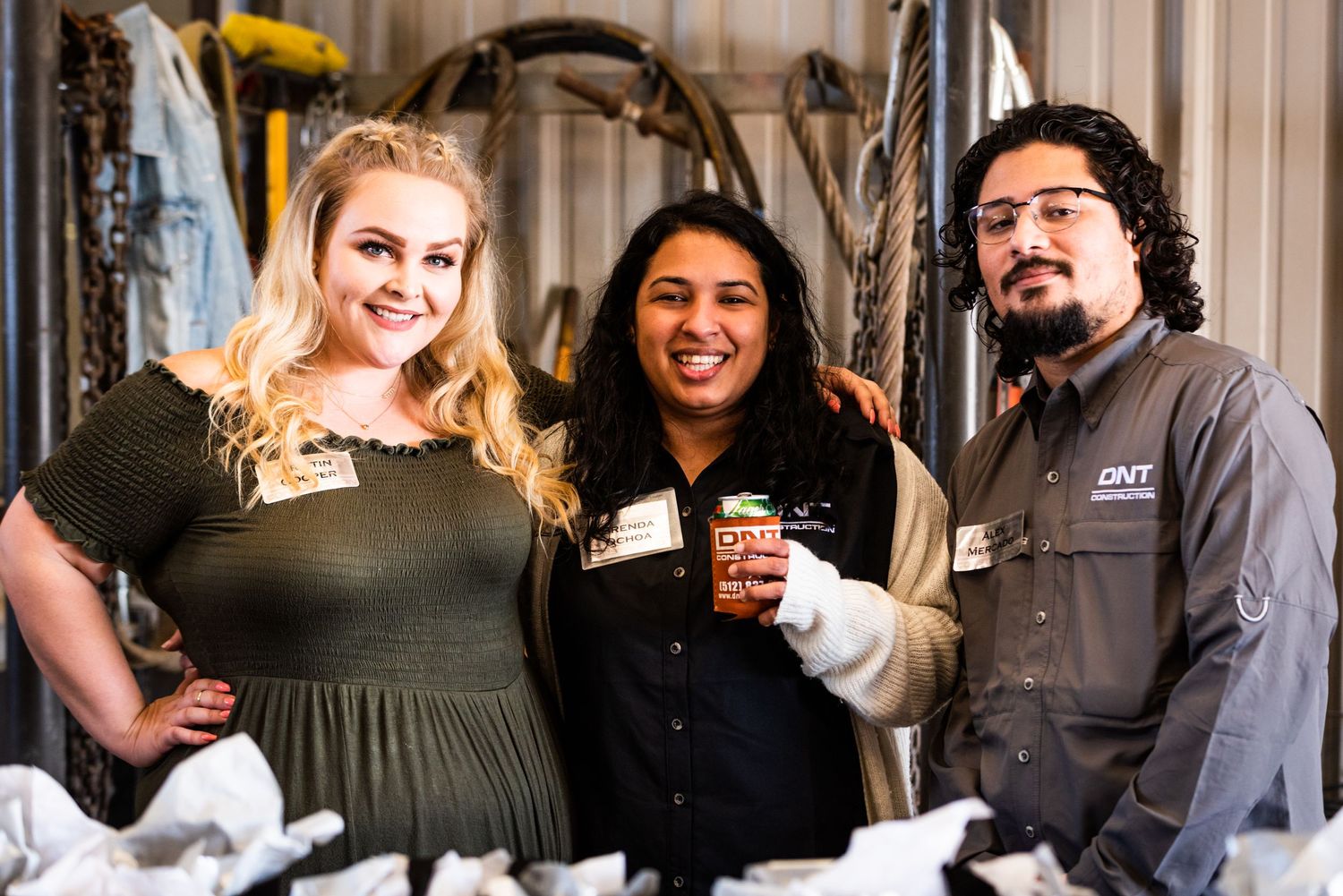 Three people posing together at an indoor event.