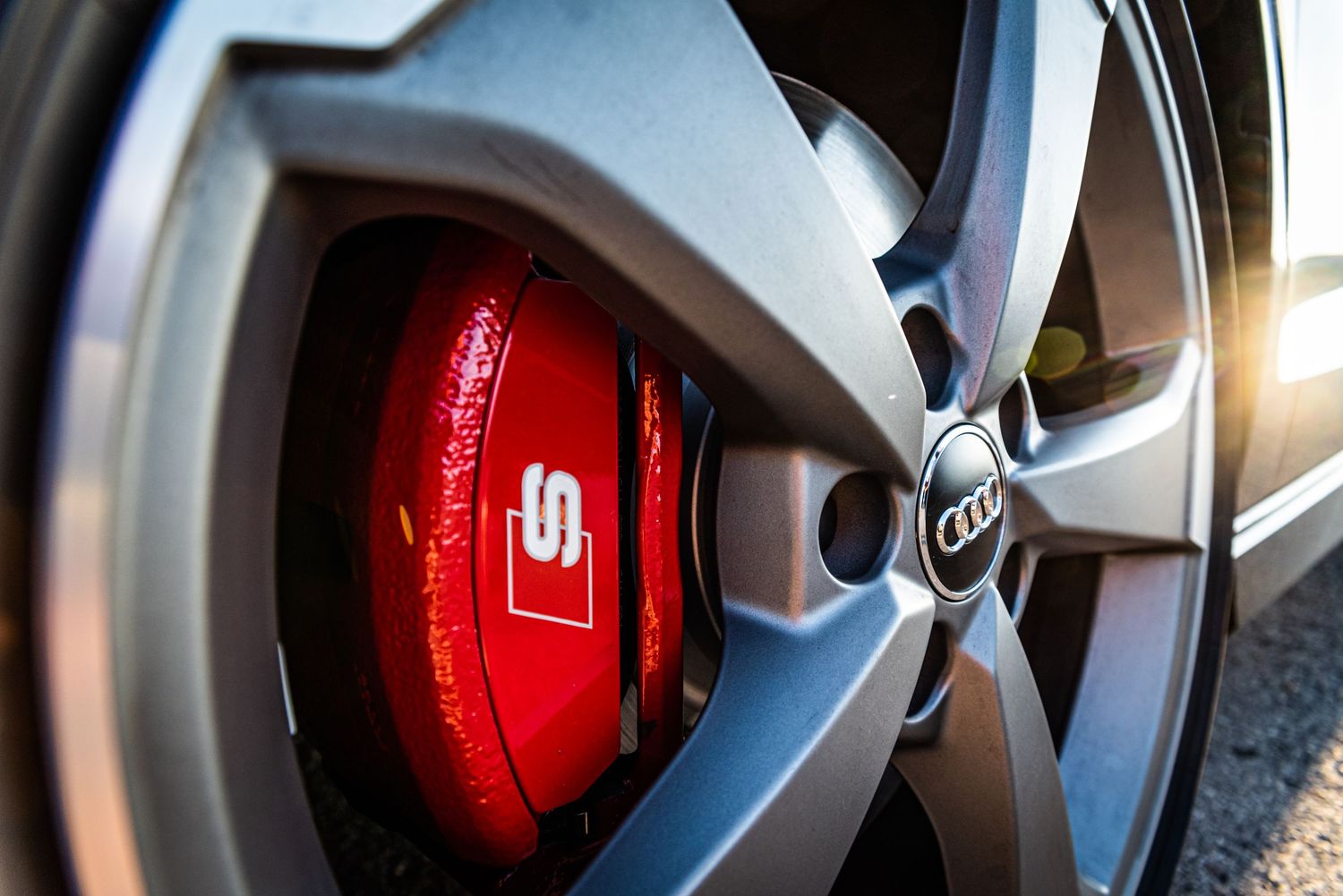 Close up of an Audi S-line red brake caliper behind alloy wheel.