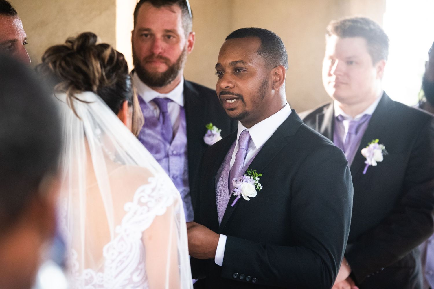 Candid shot of a bride and groom standing in front of a bright church window.