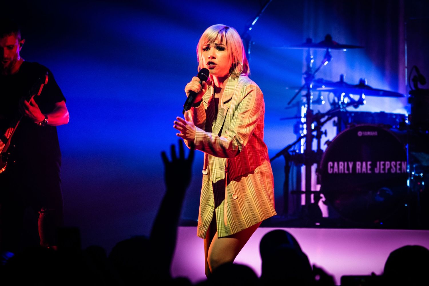 Concert stage bathed in blue light with performer singing into microphone.