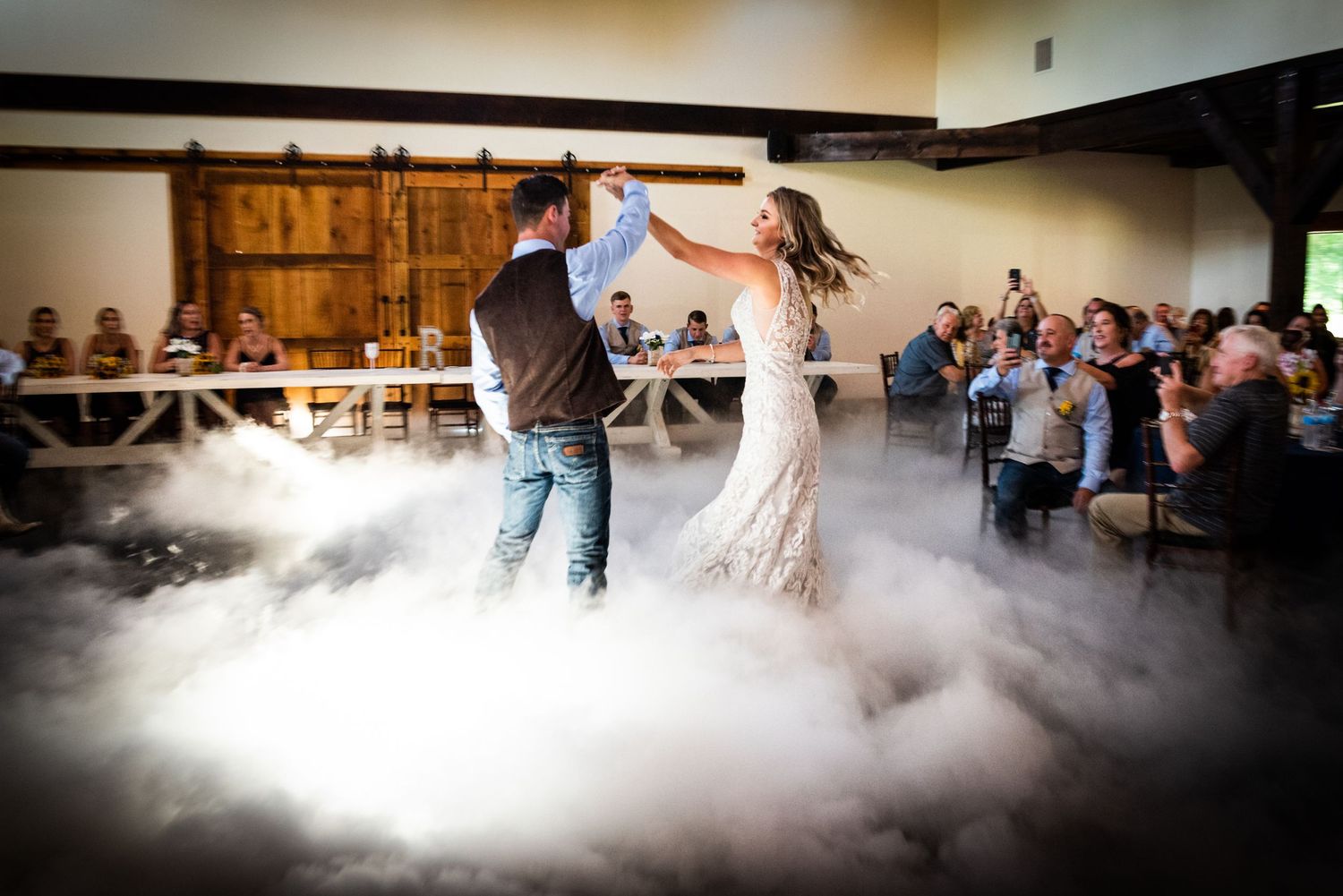 Couple dances their first dance surrounded by romantic fog effects on the dance floor.