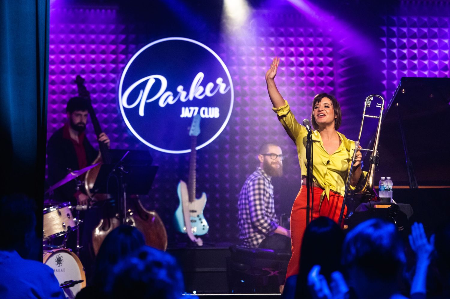 A jazz performance at Parker Jazz Club features energetic musicians under bright stage lights.
