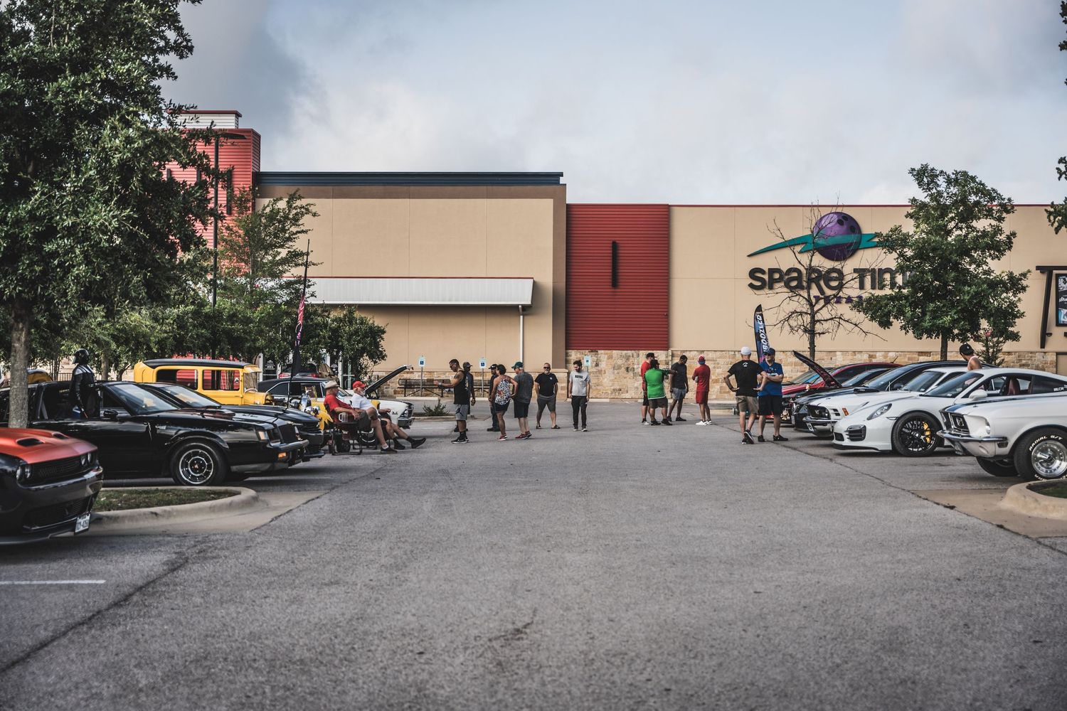 Sports cars parked outside a retail shopping center with spectators.