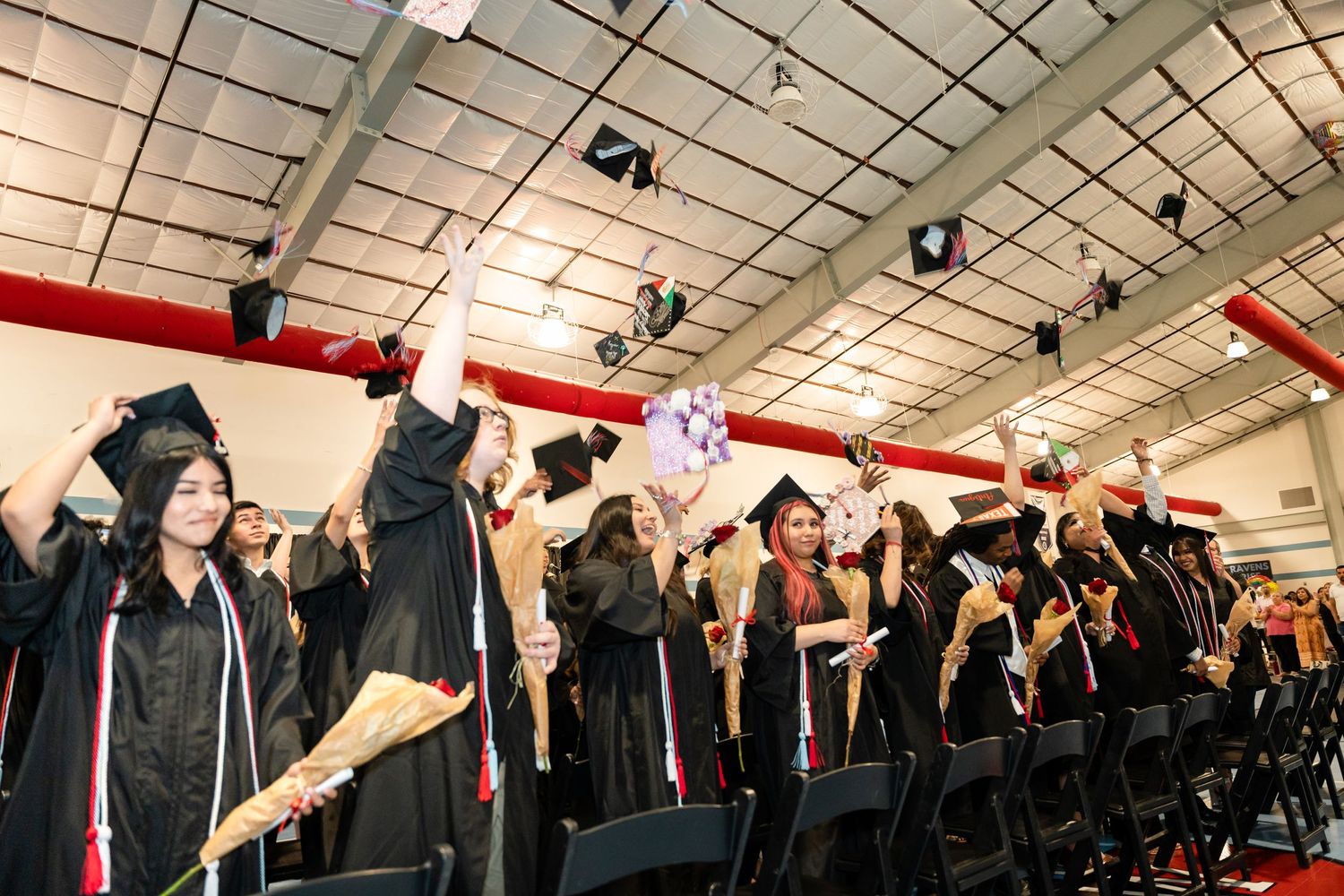 Excited graduates throw their caps in the air during graduation celebration.
