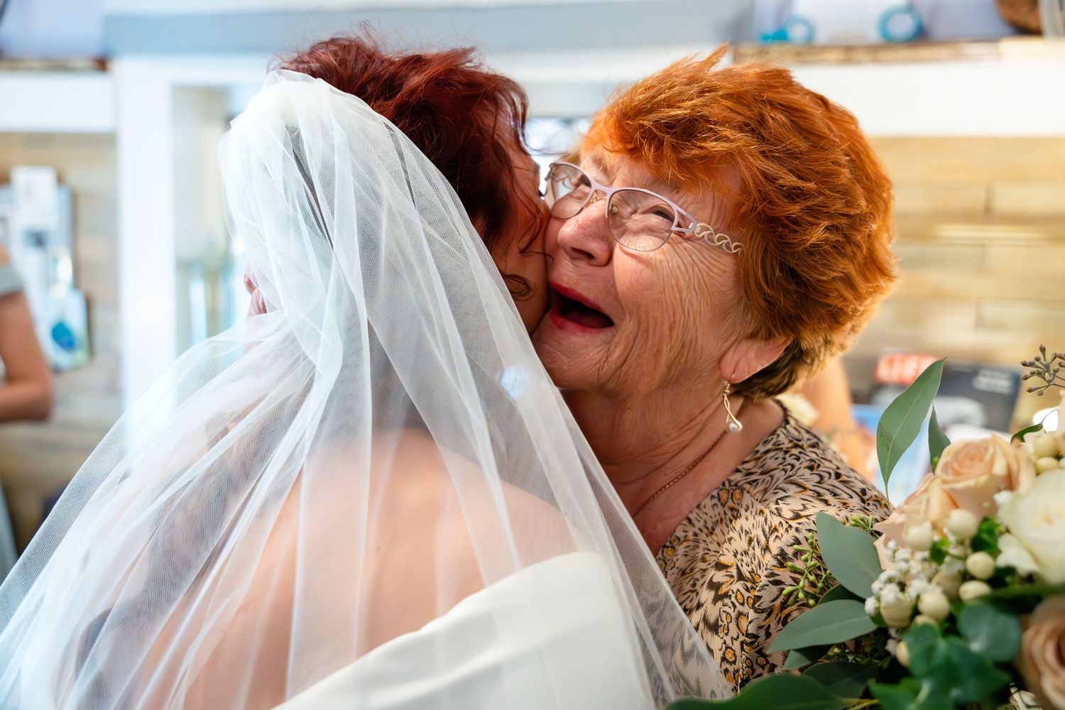 Joyful emotional embrace captured during wedding celebration with floral decorations.