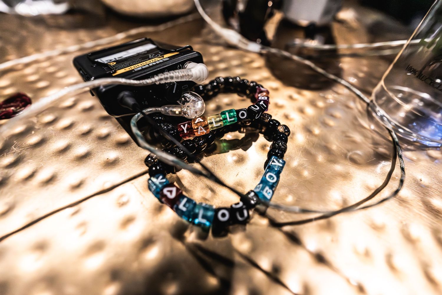 Close-up of guitar picks and bracelets arranged on textured metallic surface.