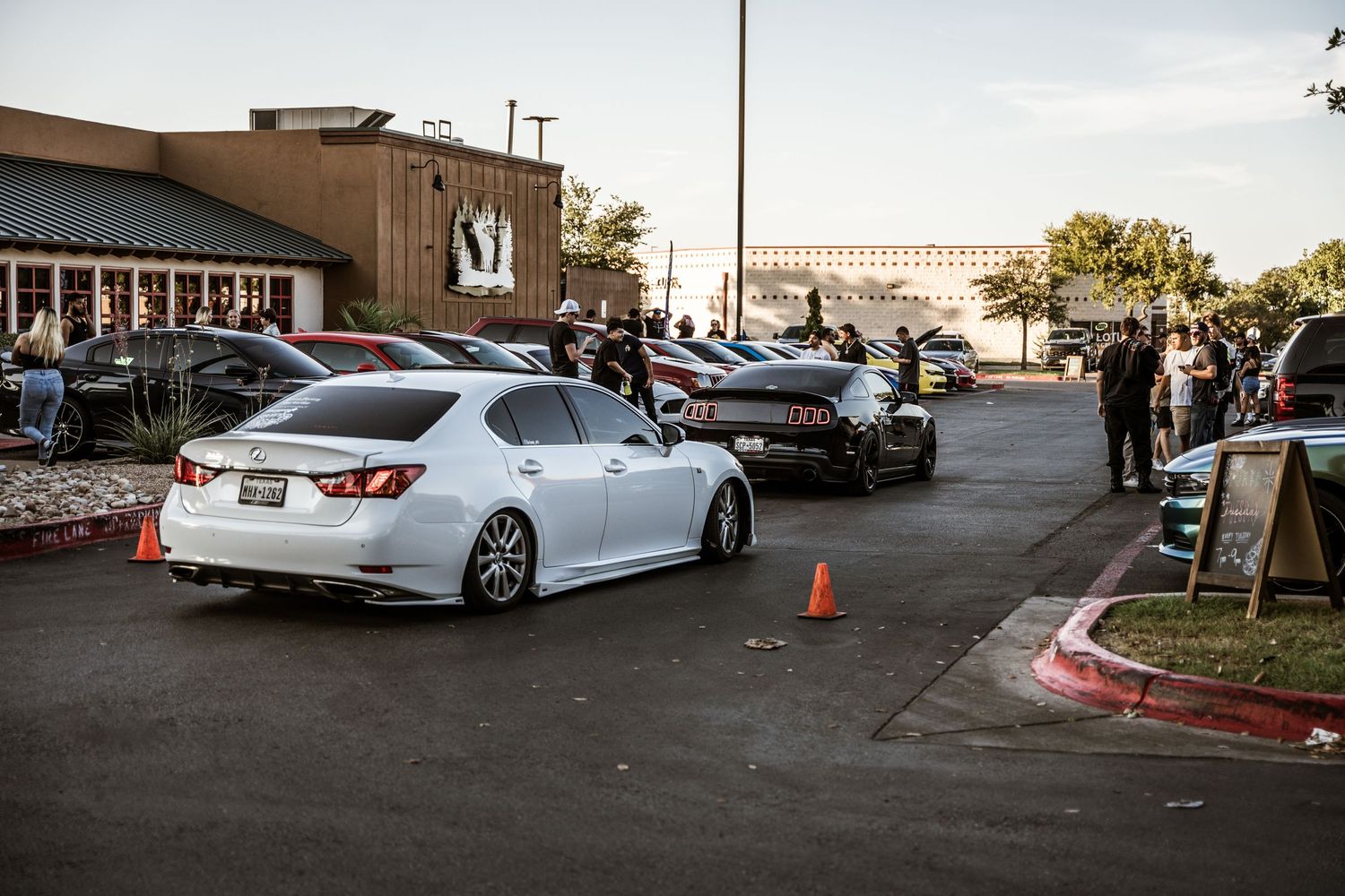 White sedan parked in commercial parking lot with orange traffic cones.