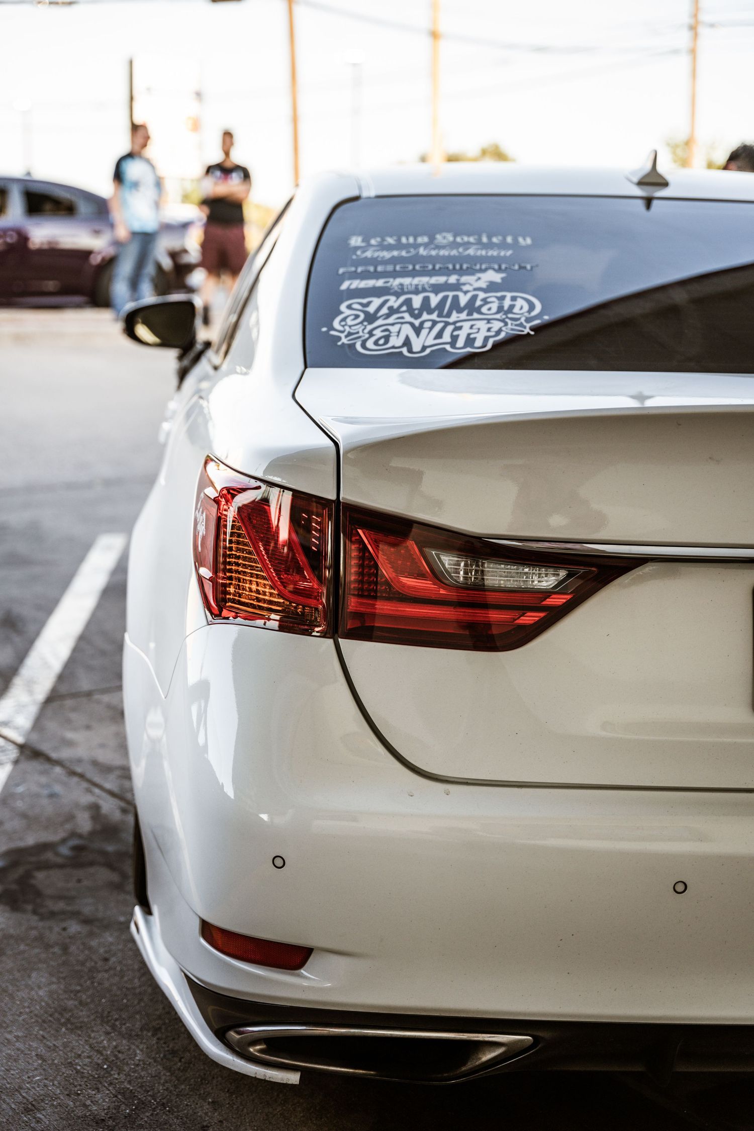 Close-up of a white luxury sedan's rear tail light with a window decal.