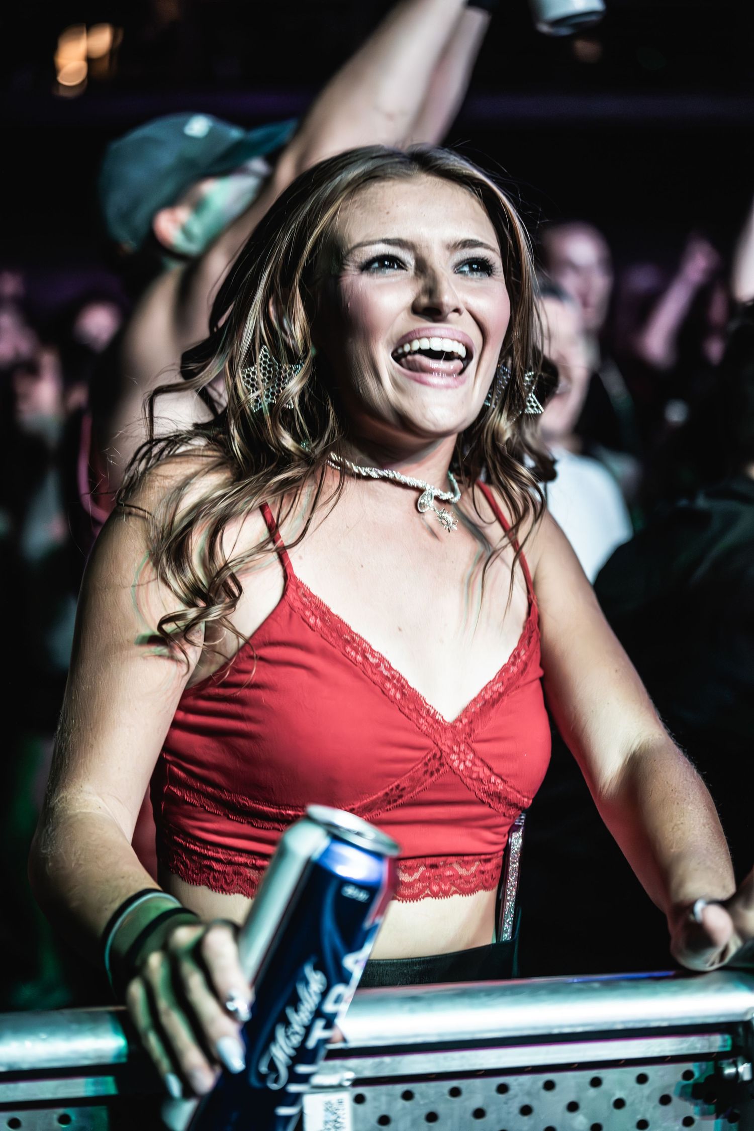 Concert attendee in red top laughs joyfully while enjoying show.