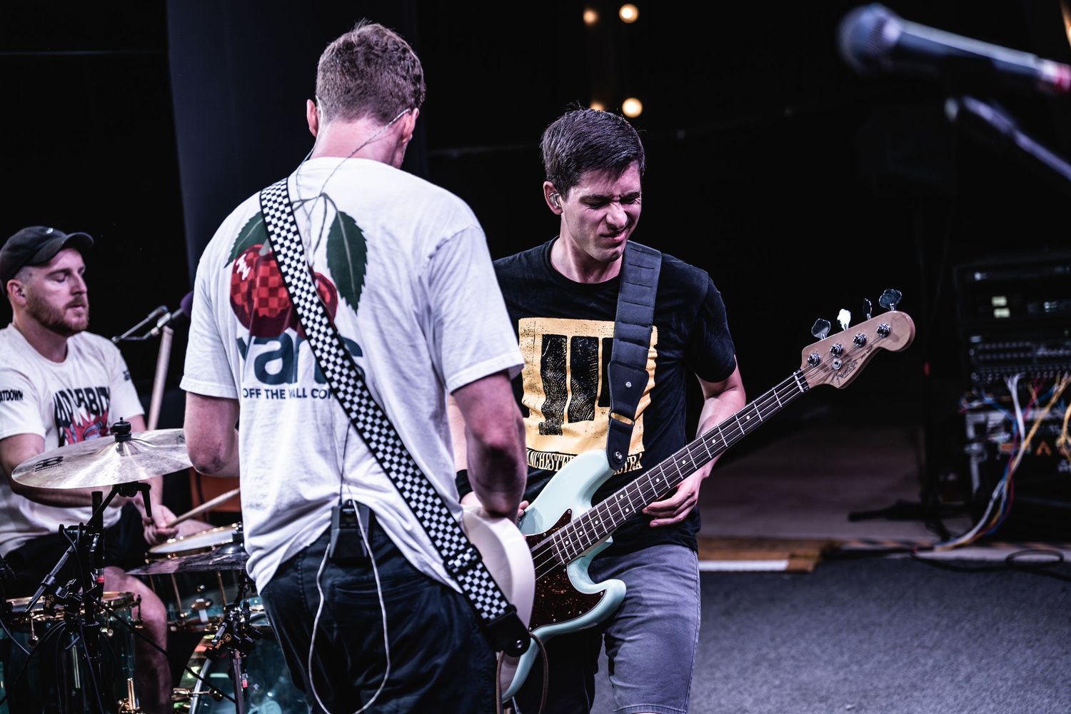 Musicians performing on stage with guitars and drums during a live concert performance.