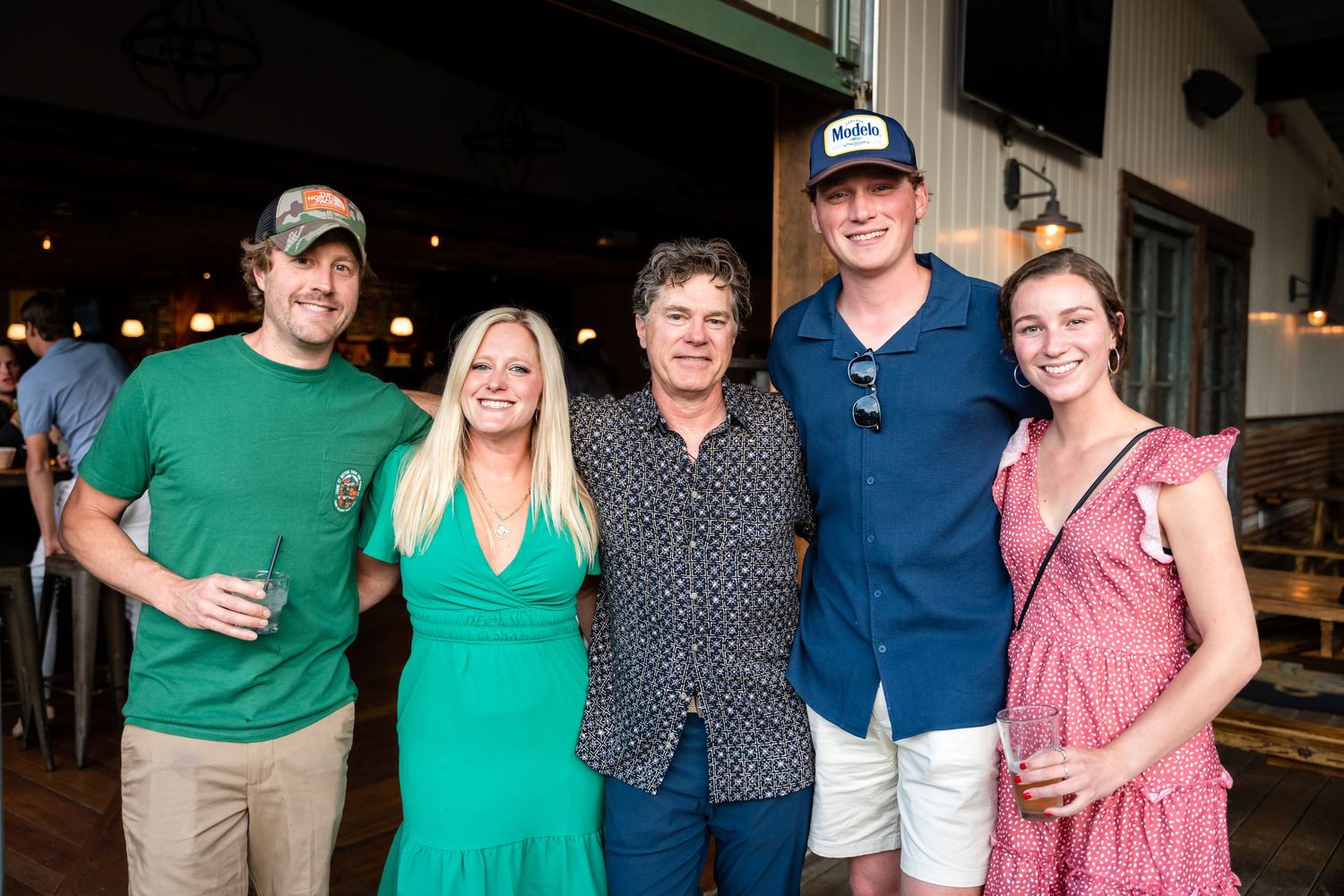 A group of friends posing together at a social gathering in casual summer attire.