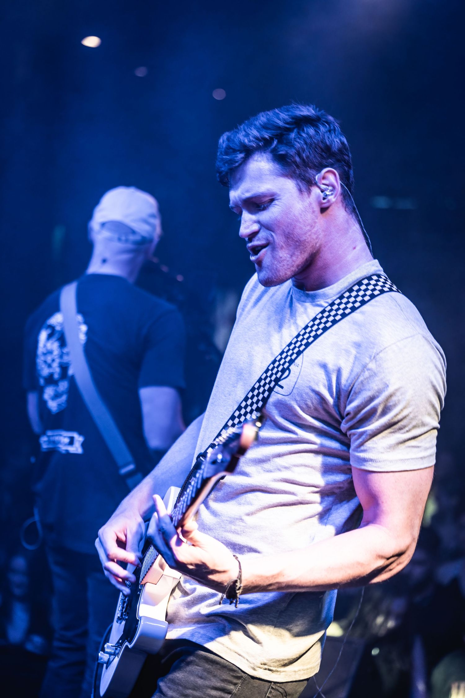 Guitarist performing on stage bathed in blue lighting during live concert.