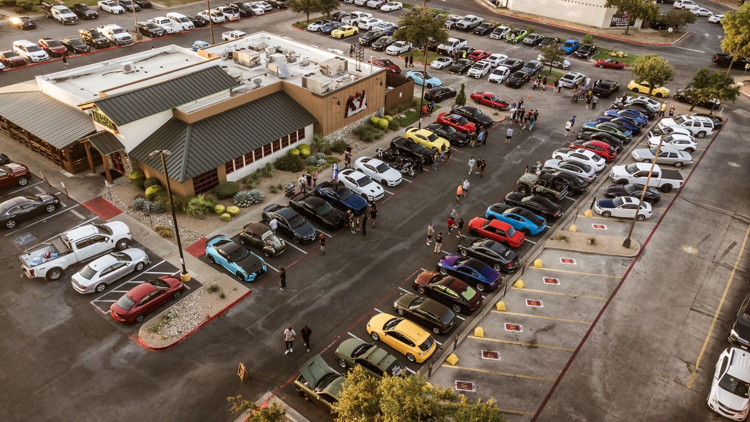 Aerial view of a parking lot filled with cars at a car show event.