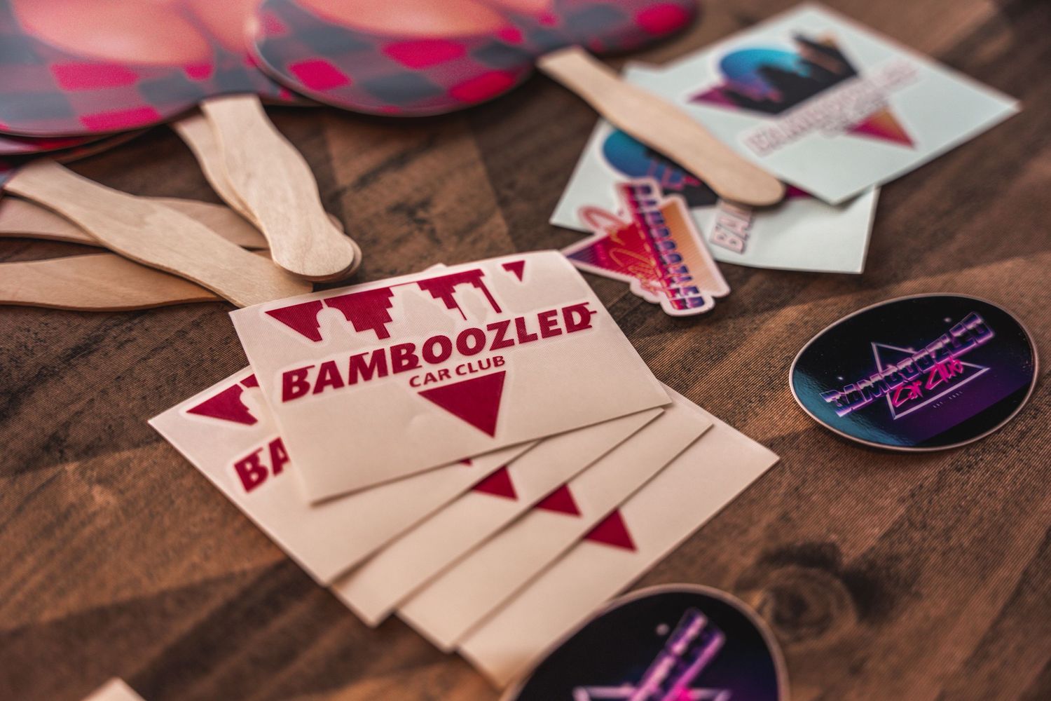Custom car event badges and lanyards laid out on wooden table.