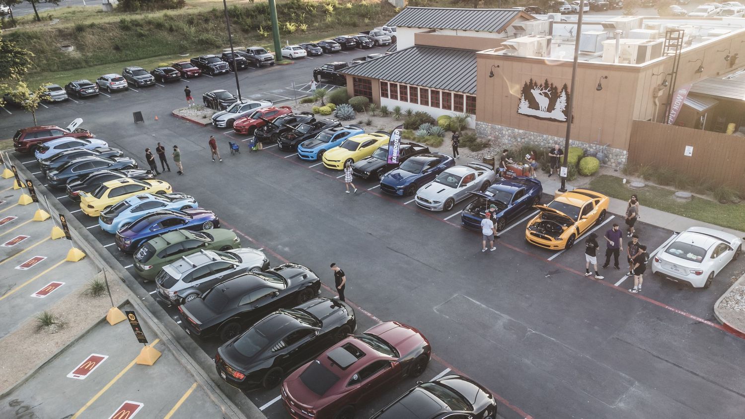 Aerial view of cars parked in rows at outdoor car meet event.