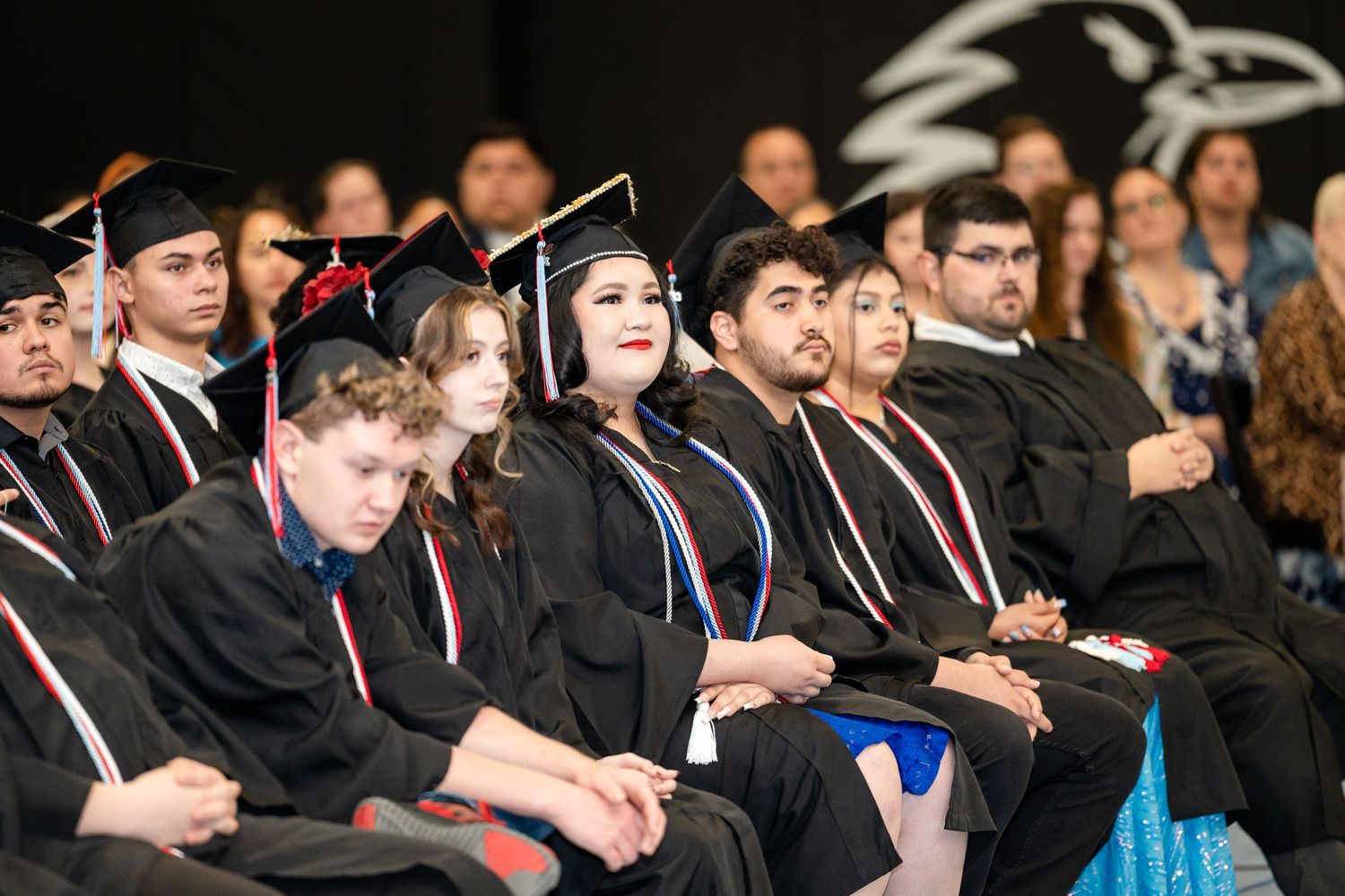 Graduates in black caps and gowns seated during commencement ceremony.