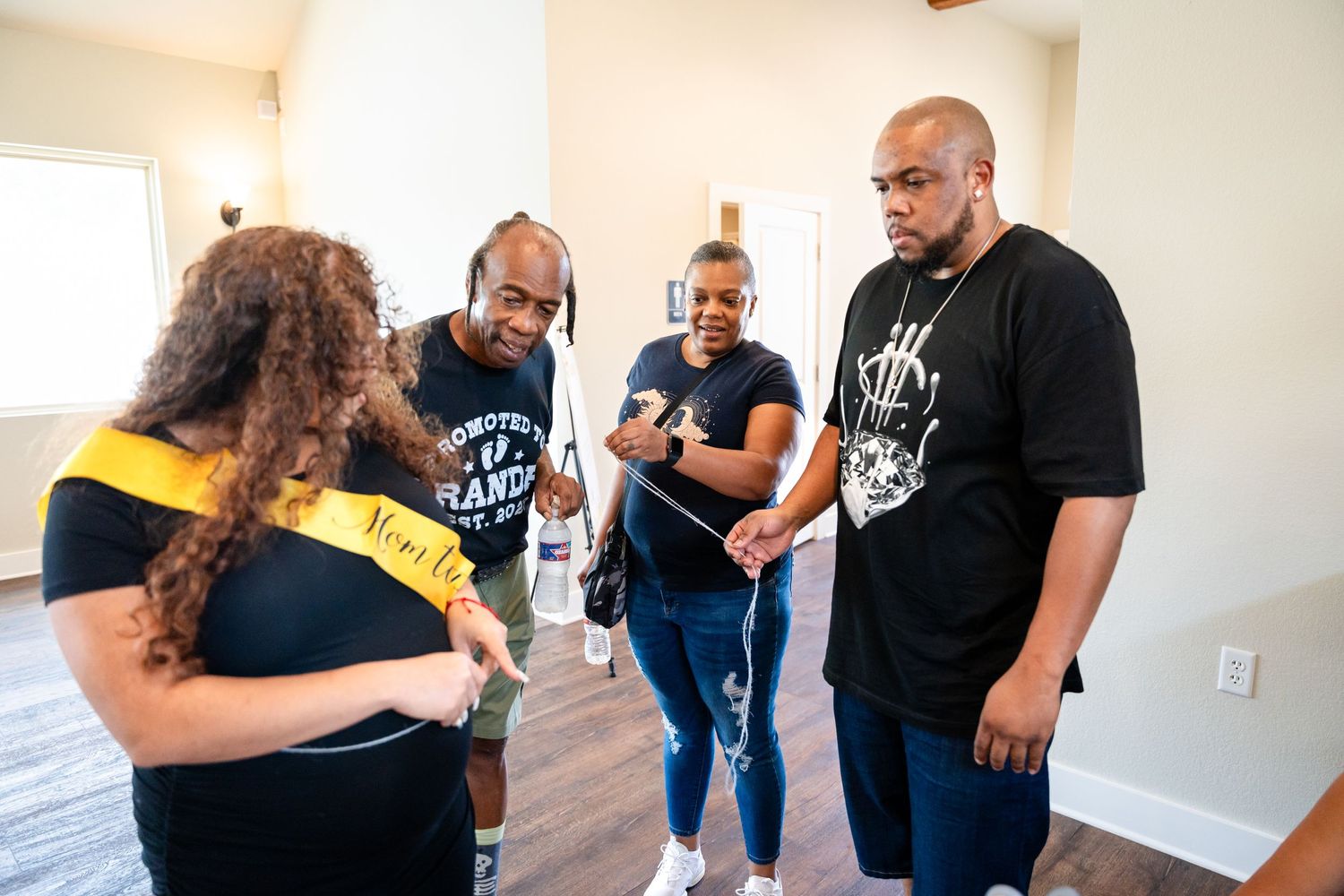 A group stands together during a baby shower celebration wearing casual attire.