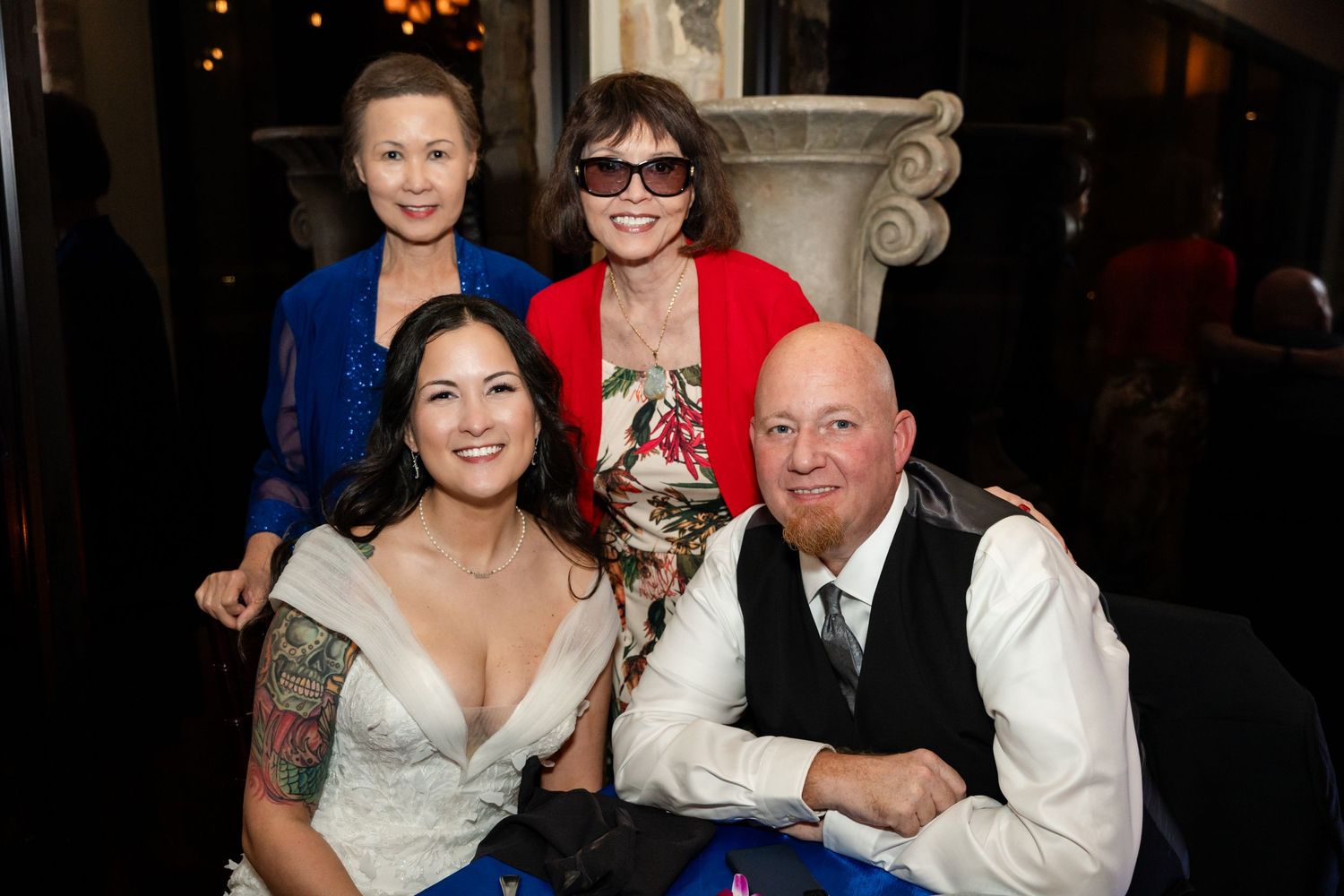 Wedding celebration with guests seated at a table featuring blue decor and formal attire.