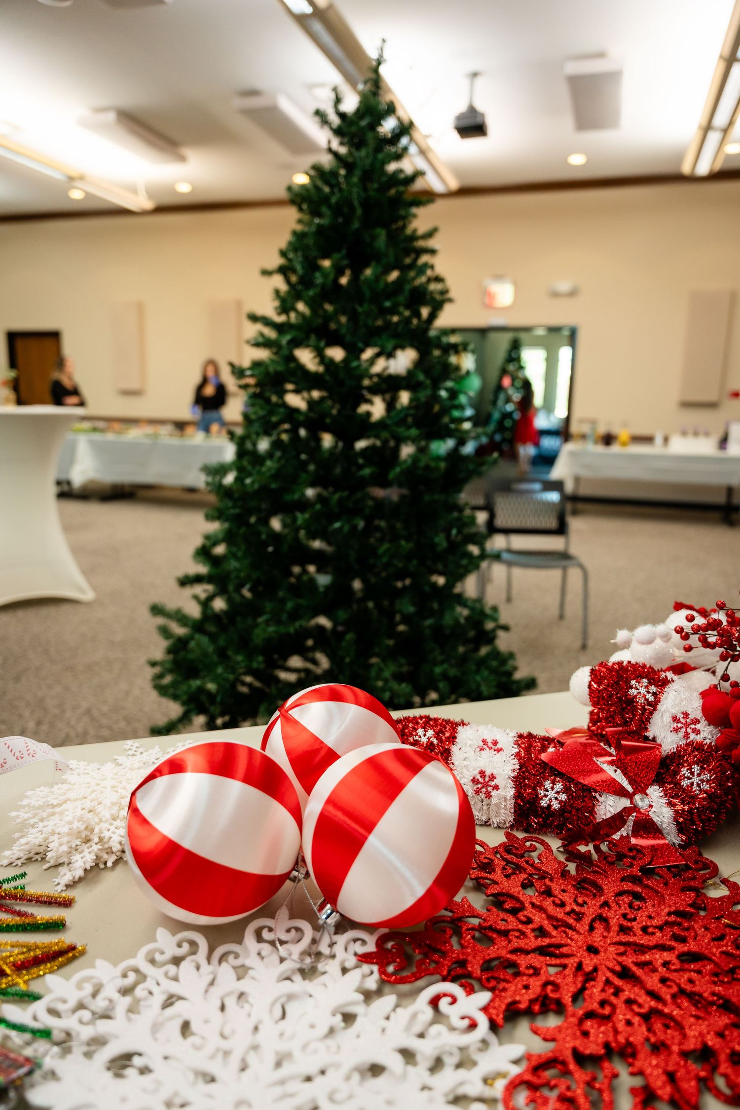 Red and white striped ornament balls and snowflake decorations beside a Christmas tree.